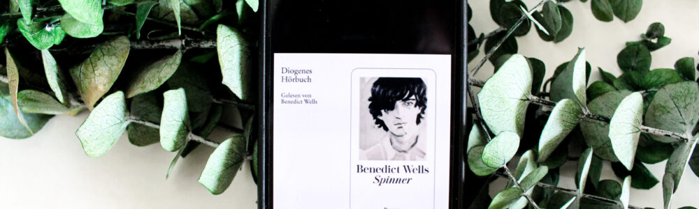 Smartphone Screen zeigt Hörbuchcover von Spinner von Autor Benedict Wellt vor Eucalyptuszweigen