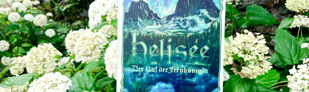 Eine Hand hält das Buch Helisee vor einem Strauch weisser Hortensien. Im linken, oberen Hintergrund ist eine Wiese zu sehen, quer über das Bild hinter dem Strauch versteckt eine Steinmauer.